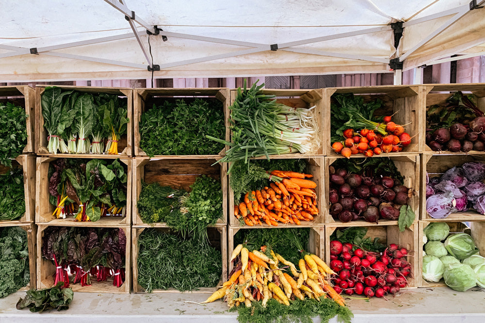 A variety of vegetables are displayed in wooden crates